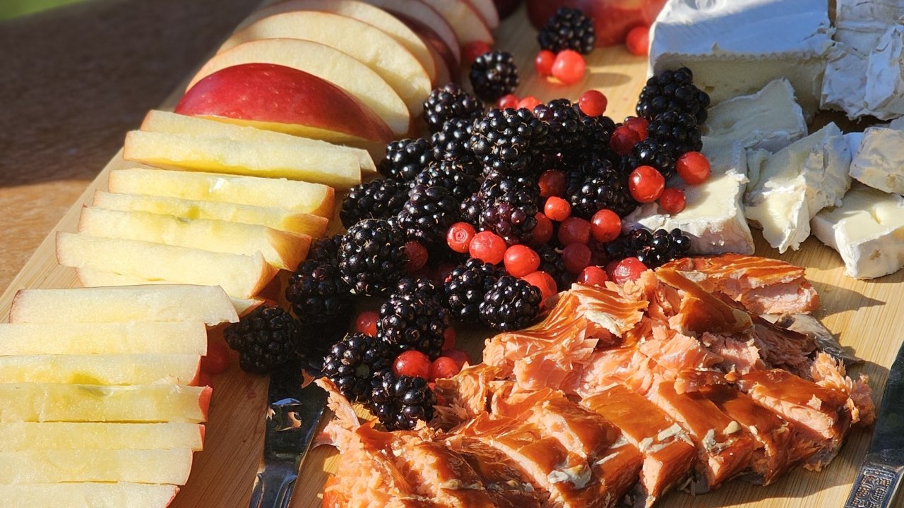Outdoor picnic spread with smoked salmon, local cheese, apples, and fresh berries during an Oregon bike tour