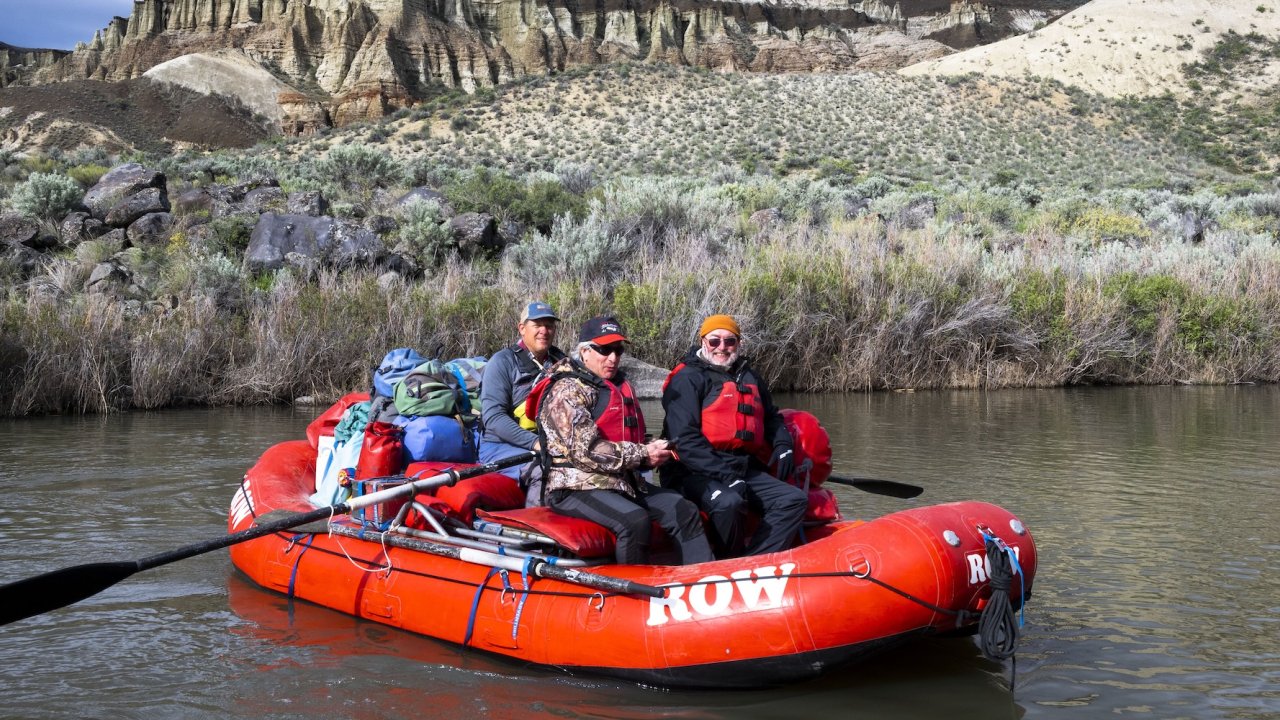 A group of rafters on a ROW Adventures red raft floating down the Owyhee river.