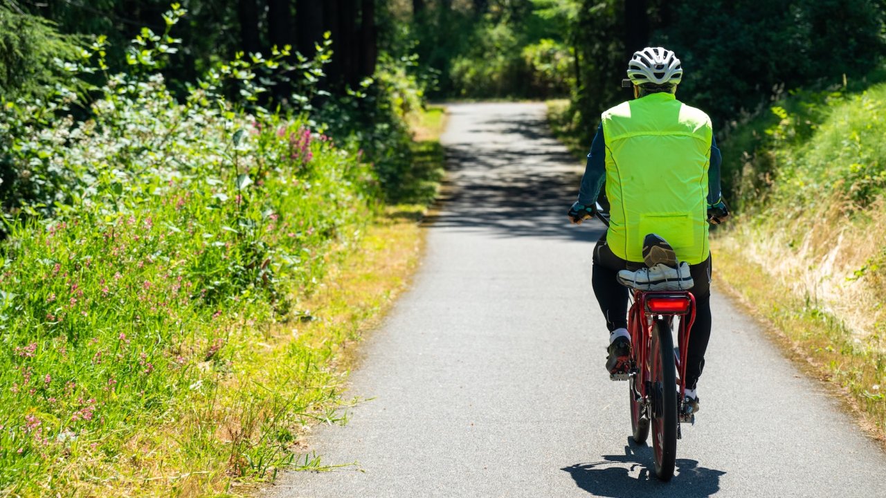 Cyclist riding on a peaceful, tree-lined bike path in Oregon, surrounded by lush greenery