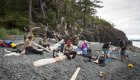 Guests sprawl gear on the beach at their stop for lunch while sea kayaking