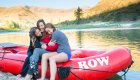 A mom with her two daughters sitting beside her on a red whitewater raft along the Salmon River