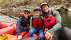 A dad and his two sons on a red raft smiling together