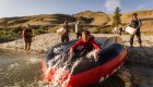 A boy sliding down the backside of a red raft during golden hour on the Lower Salmon River