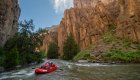 A red ROW raft floating down the Bruneau river with towering canyon walls on either side