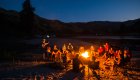 Group of people around a campfire on a sandy beach along a river in Idaho