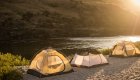 Three tents set up on a white sand beach along the Salmon River during golden hour in Idaho