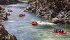 A lineup of red raft floating down the Clark Fork River in the Alberton Gorge in Montana