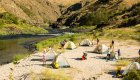 A sandy beach full of tents and rafters in the morning as they pack up for a day on thr river