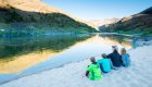 A mom and her three kids sit beside her on a sandy beach along the Salmon River in Idaho