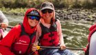 A mom and sun wearing sunglasses and smiling with each other while rafting with ROW Adventures in Idaho