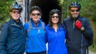 Four people all wearing helmets smiling while on a group bike tour