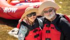 A couple sitting on a red whitewater raft smiling