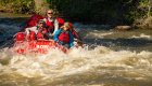 People smiling while being rowed through a whitewater rapid on the Bruneau River in Idaho