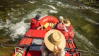 Top down view of a red whitewater raft with a guide, and three guests in the sun in Idaho