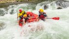 A group of people in a red raft paddling through a whitewater rapid in Idaho