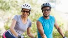 Husband and wife smiling on their bikes with helmets and sunglasses on