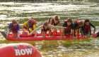 A row of kids on top of an upside down inflatable kayak in the Salmon River