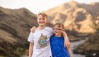 Two brothers under the age of 10 smiling while on a hike together in Idaho