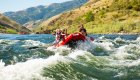 Family paddling through a rapid in a red boat on the Lower Salmon River