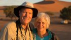 A man on the left and woman on the right smiling while on safari in Africa at sunset
