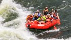 A red raft full of guests and one guide about the enter a wave in a rapid on the Clark Fork River