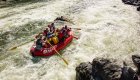 Shot from behind a red whitewater raft moving downstream through a rapid on a sunny day on the Rogue River