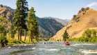 A red raft floating on the Middle Fork Salmon River on a sunny day