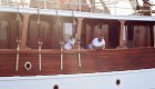 female leaning over side deck of wooden yacht