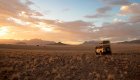 Safari jeep on the right enjoying sunset in the wide open desert of the Namib Rand Nature Reserve