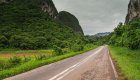 Wide open road with a white double line down the center in a lush green landscape in western Cuba