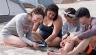 family sitting in a circle looking at a book together in the sand in Baja California Sur