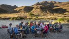 Guests around the table eating dinner riverside while camping along the Snake River through Hells Canyon