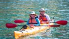 Travelers paddle a tandem sea kayak on calm coastal waters in Corsica as part of a small-group Corsica tour.