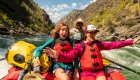 mom and daughter with outstretched arms on front of whitewater raft