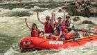 group of girls raising their arms in whitewater raft