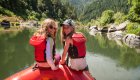 two girls sitting on front of whitewater raft