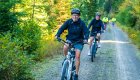 Group of cyclists riding along a forested gravel trail 