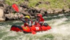 Two paddlers smiling while navigating splashy rapids in an inflatable raft.