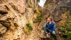 Hiker sitting near red pictographs painted on a rocky canyon wall.