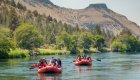 Three red rafts floating along the Deschutes river in Oregon