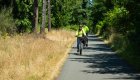 E-bike riders cruising along a paved, tree-lined rail trail in Oregon, part of the Row River and Banks-Vernonia trail experience