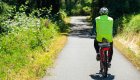 Cyclist riding on a peaceful, tree-lined bike path in Oregon, surrounded by lush greenery