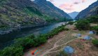 Panoramic view of a riverside camp with tents set up along the Snake River Hells Canyon at sunset