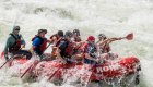 A group of people paddling through a whitewater rapid with a guide in the back on the Snake River through Hells Canyon