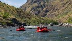 Two red rafts carrying guests through calm stretches of the Salmon River in Idaho, a whitewater rafting journey paired with wellness retreat elements.
