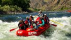 A red raft full of passengers paddling through a whitewater rapid on a sunny day