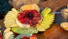Baked brie with fruit and crackers served on a riverside camp table.