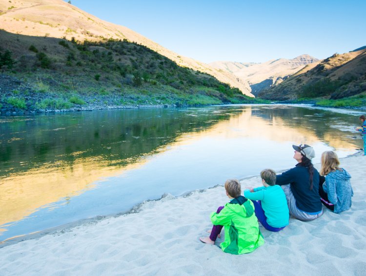 A family sitting on a beach along the lower salmon river in Idaho