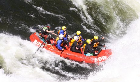 Six paddlers with yellow helmets in a red raft paddling through a big whitewater rapid on the Lochsa River in Idaho