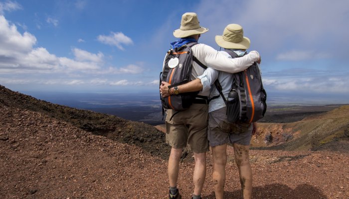 Two travelers with sun hats side hugging while enjoying the view of the Galapagos Islands